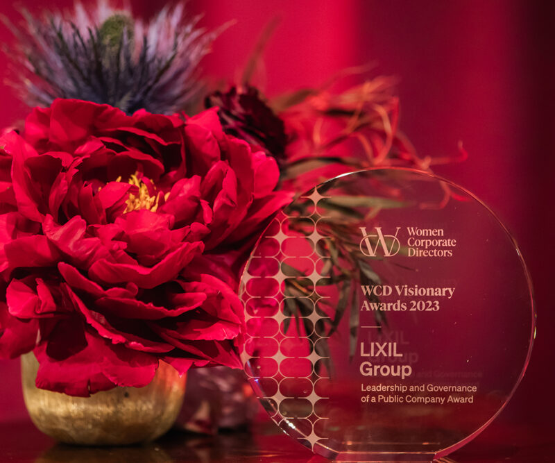 An award staged on a table next to a flower arrangement with a red curtain in the background